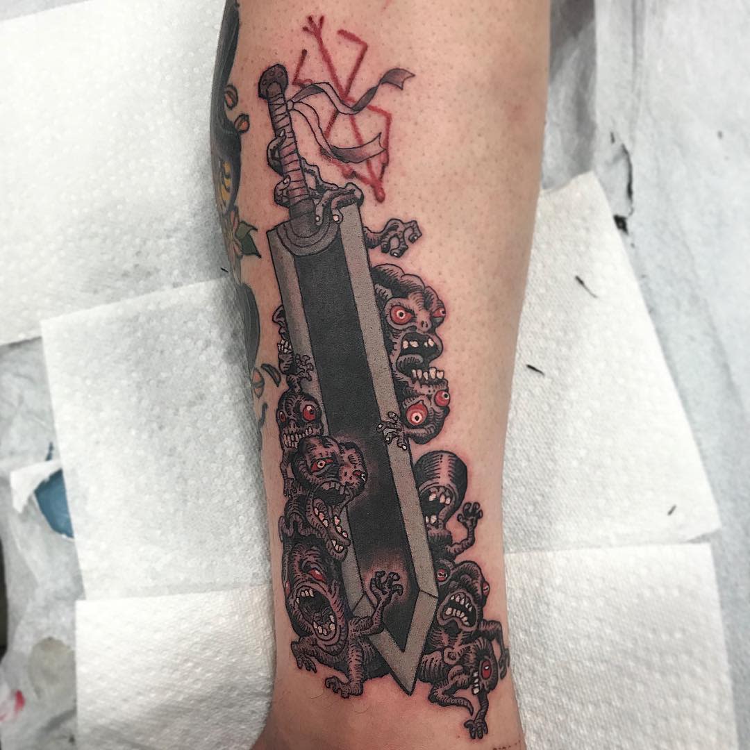 Tattoo of Guts' Dragon Slayer sword from Berserk, surrounded by grotesque demonic faces and the Brand of Sacrifice in red above